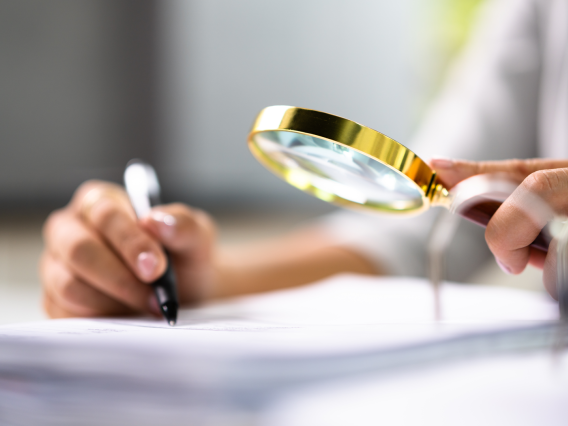 person examining document with a magnifying glass